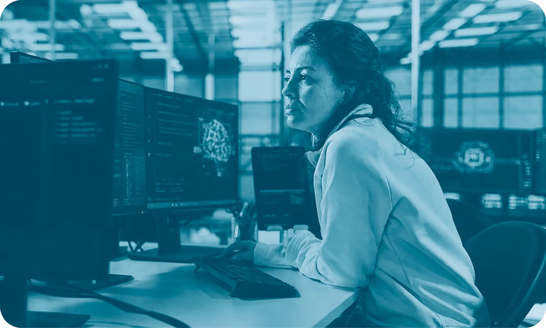 IT-Sicherheitsanalystin überwacht Systeme an mehreren Bildschirmen